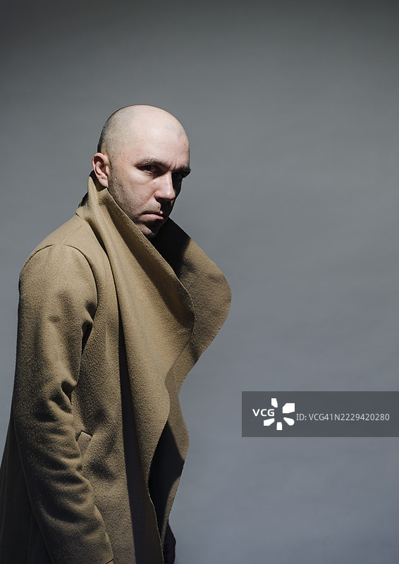 一个严肃的光头男人回头看着。图片素材