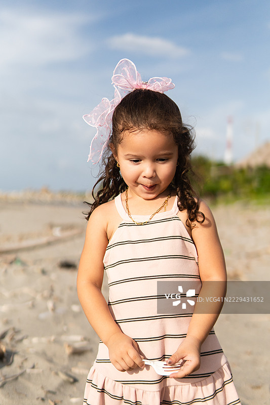 年轻女孩手持塑料叉，站在满是垃圾的海岸线上，象征着环境污染对海洋生态系统和全球可持续发展的毁灭性影响。图片素材
