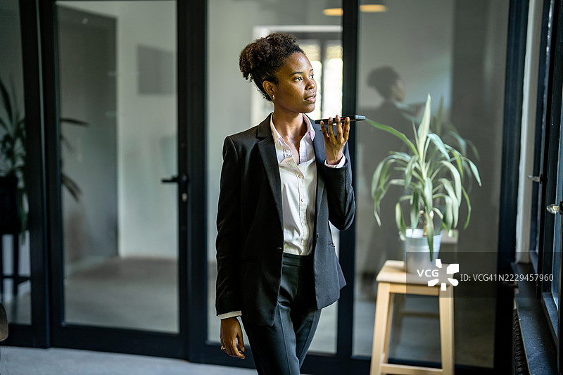女商人在办公室走廊用智能手机录制语音信息图片素材