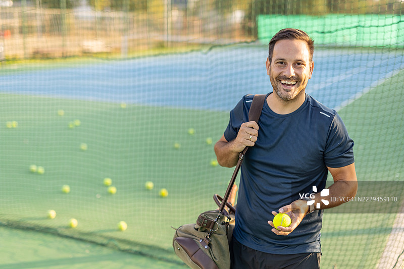 微笑并穿戴装备的放松个体在网球场上摆姿势图片素材