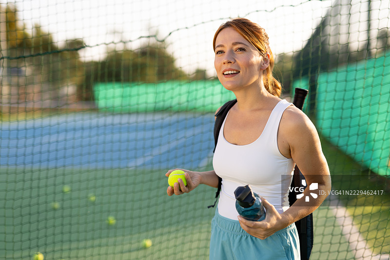 充满活力的女性在户外准备好打网球的姿势，身穿网球装备图片素材