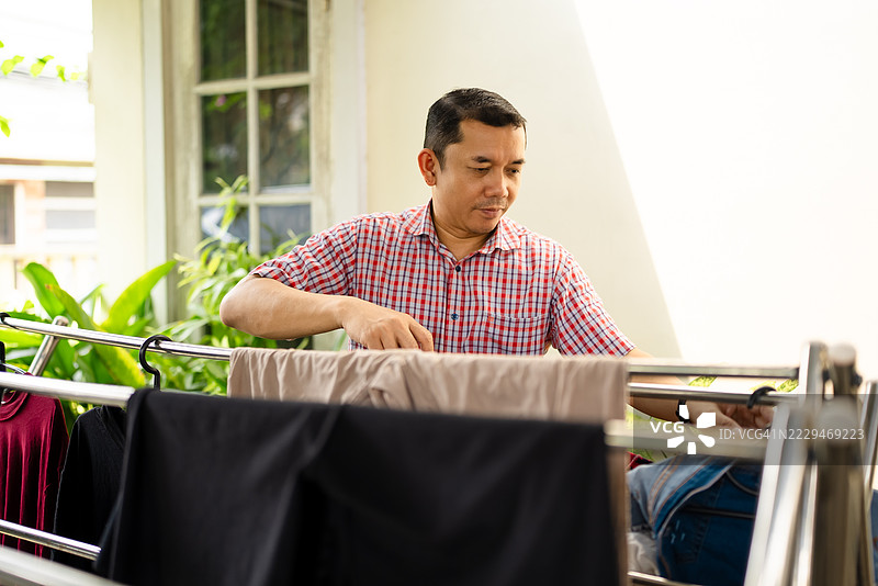 男人在家里晾衣服的架子上晒衣服图片素材