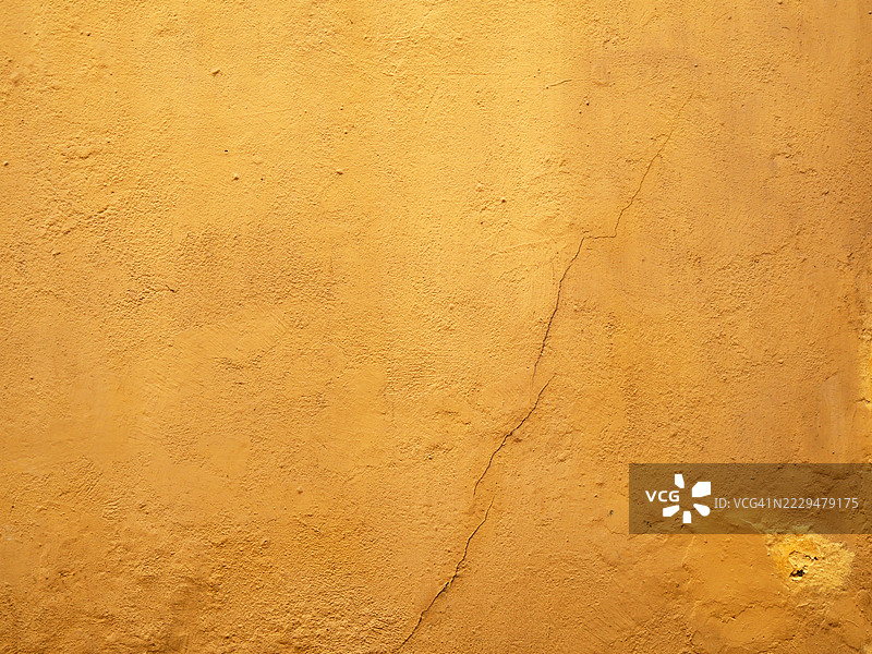 西班牙塞维利亚一面破裂的黄色混凝土墙特写。粗糙的纹理。自然色彩和风化效果。全画幅 4:3图片素材