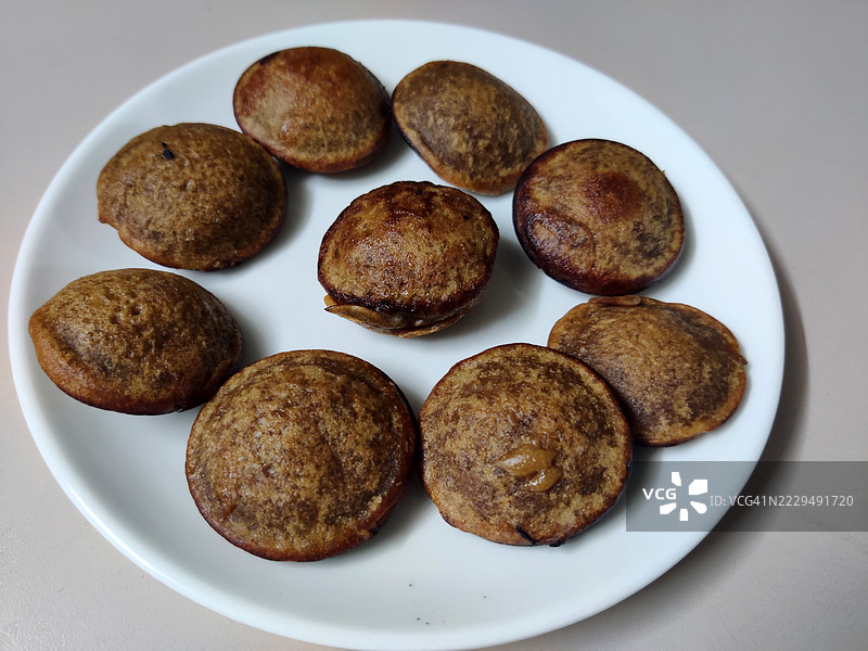 白色陶瓷盘中的自制unni appam/unniyappam/传统喀拉拉小吃特写/白色背景/奥南节/维苏节/喀拉拉图片素材