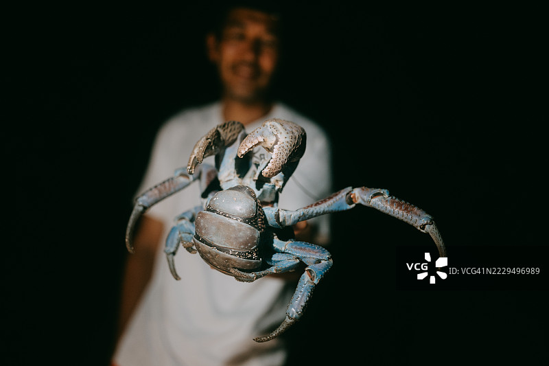 夜间在日本冲绳石垣岛，一名男子手中拿着椰子蟹图片素材