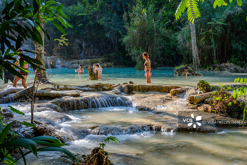 游客们在老挝琅勃拉邦附近的丛林中，于阔西瀑布碧绿的水池里游泳和放松。图片素材