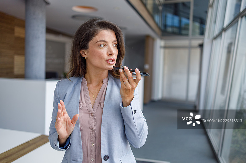 女商人在办公室使用智能手机上的虚拟助手图片素材