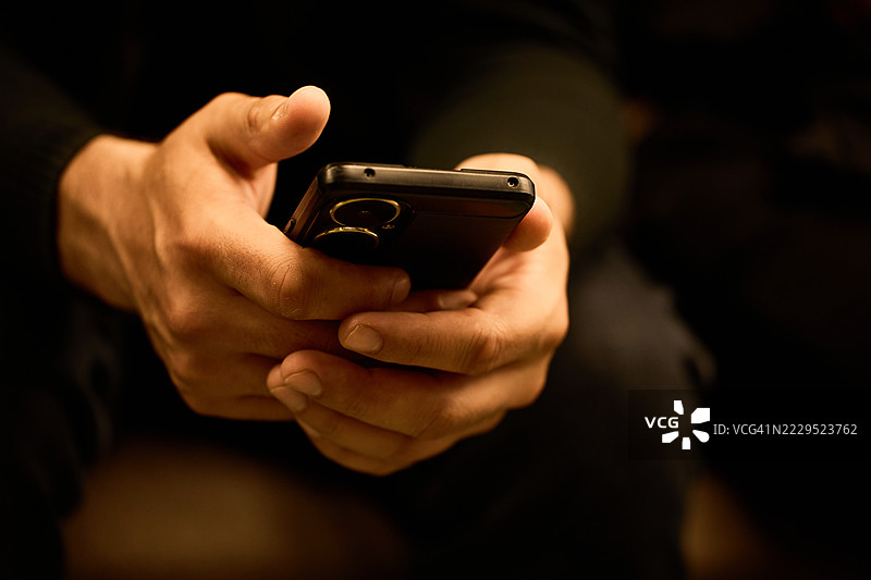 手握智能手机，屏幕显示空白，室内环境。图片素材