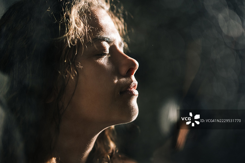 美丽的女性在淋浴中闭着眼睛。黑色背景。图片素材