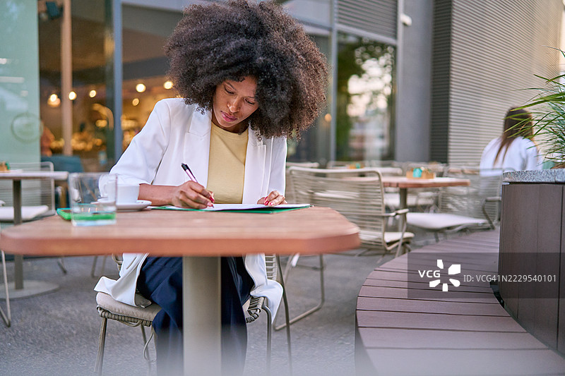在户外咖啡馆工作的女商人，正在写文件图片素材