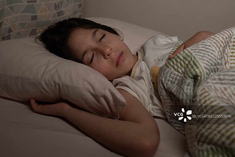 小女孩在夜晚的床上睡觉。图片素材