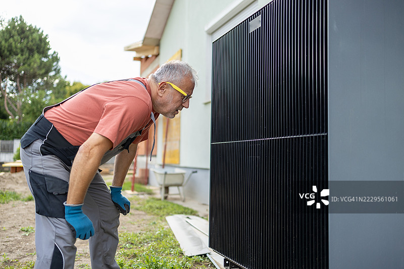 老年工人在家中安装时检查户外热泵设备图片素材