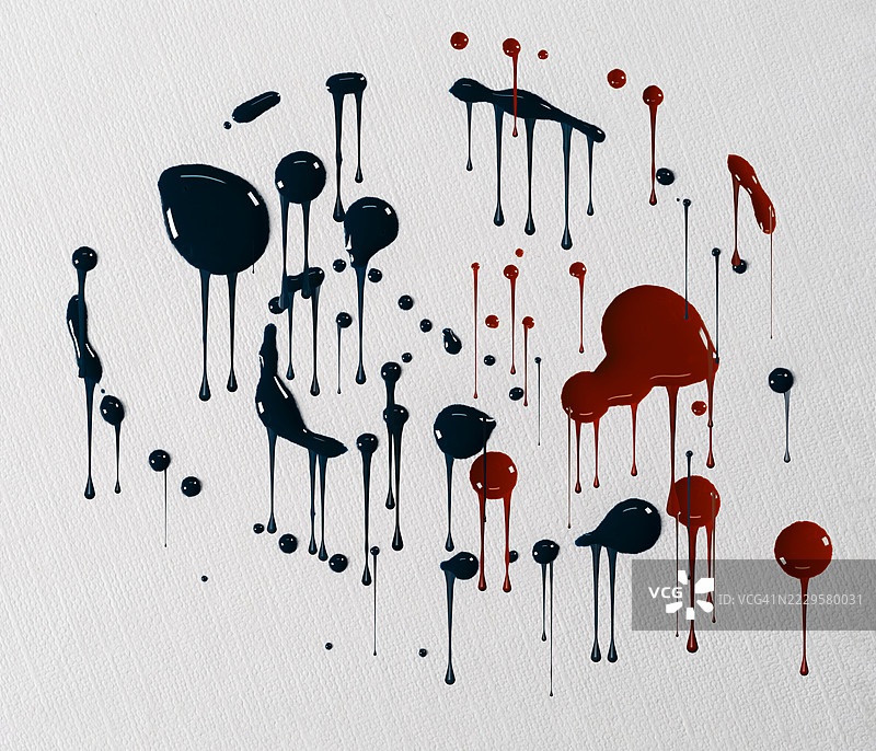 红色和蓝色的油漆滴落并滑落在白色墙壁上。图片素材