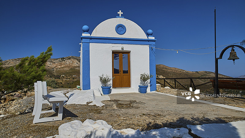 一座拥有蓝色外墙和十字架的白色小教堂，坐落于开阔的山区景观中，帕纳吉亚图帕莱奥卡斯特罗，旧堡教堂，帕纳吉亚卡斯特利，莱皮德斯，莱罗斯，佐泽卡尼索斯，希腊群岛，希腊图片素材