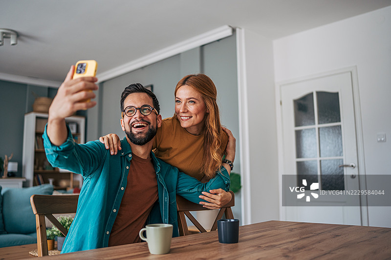 幸福的情侣在温馨的客厅里自拍图片素材