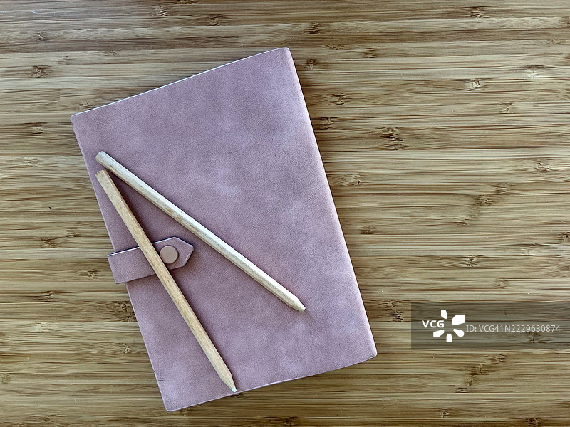 粉色日记本与铅笔放在木桌上图片素材