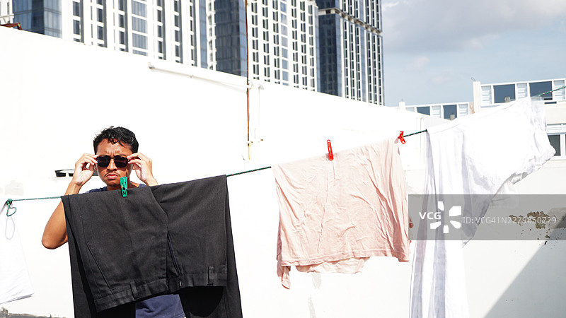 男人在阳光下晾衣服时戴着太阳镜图片素材