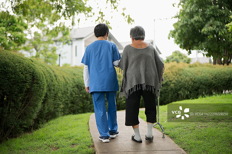 老年妇女在公园里与护理人员一起散步锻炼。图片素材