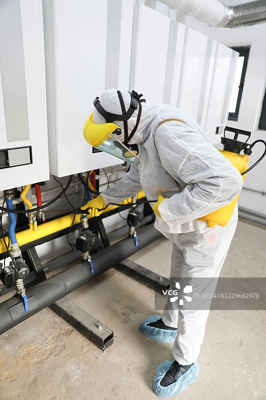 穿着白色工作服的老年工人在消毒燃气锅炉房图片素材
