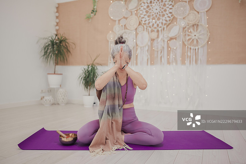 坐在垫子上双手合十冥想的女性图片素材