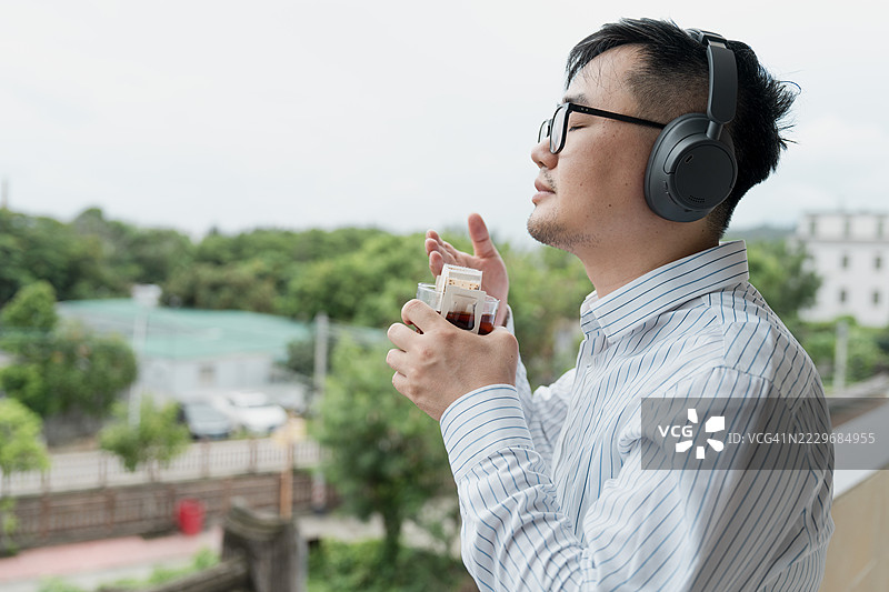 亚洲男性在阳台上喝咖啡放松心情；工作氛围图片素材