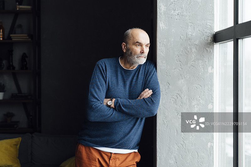 站在窗前，双臂交叉的老年人图片素材