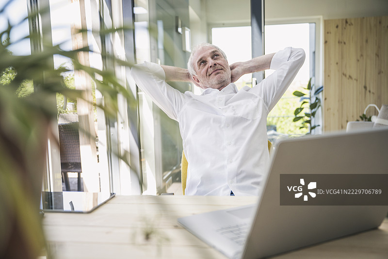 在家中，双手放在头后，做白日梦的资深自由职业者图片素材