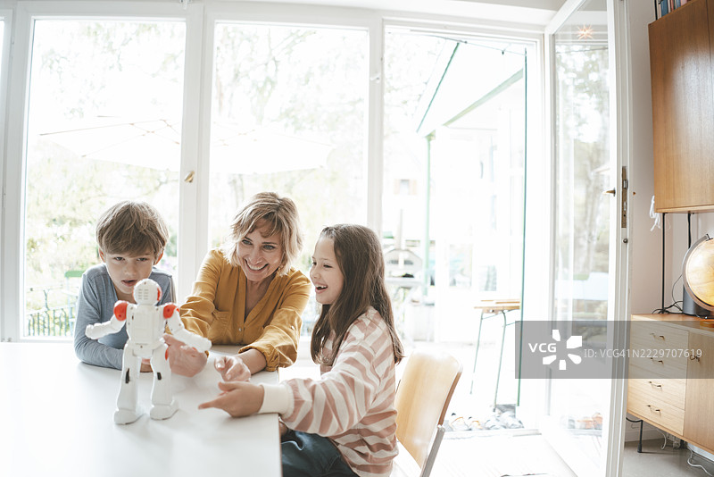 快乐的家庭在桌子旁一起玩玩具机器人图片素材
