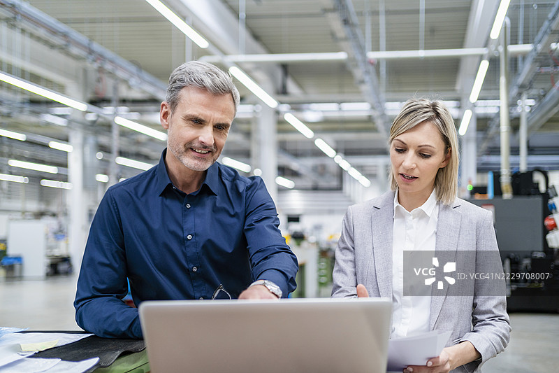 商人和女商人在工厂一起使用笔记本电脑工作图片素材