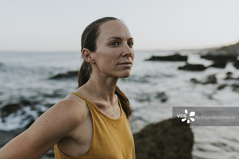 在日落时分，沉思的女性站在海岸边图片素材