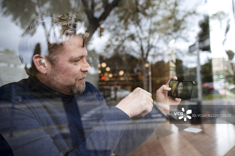 商人在咖啡馆通过智能手机与女友视频通话图片素材