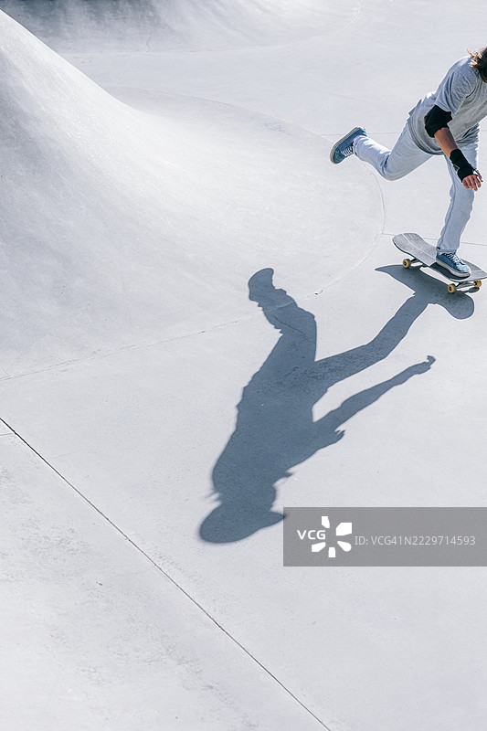 阳光明媚的日子里，男子在滑板公园滑板。图片素材