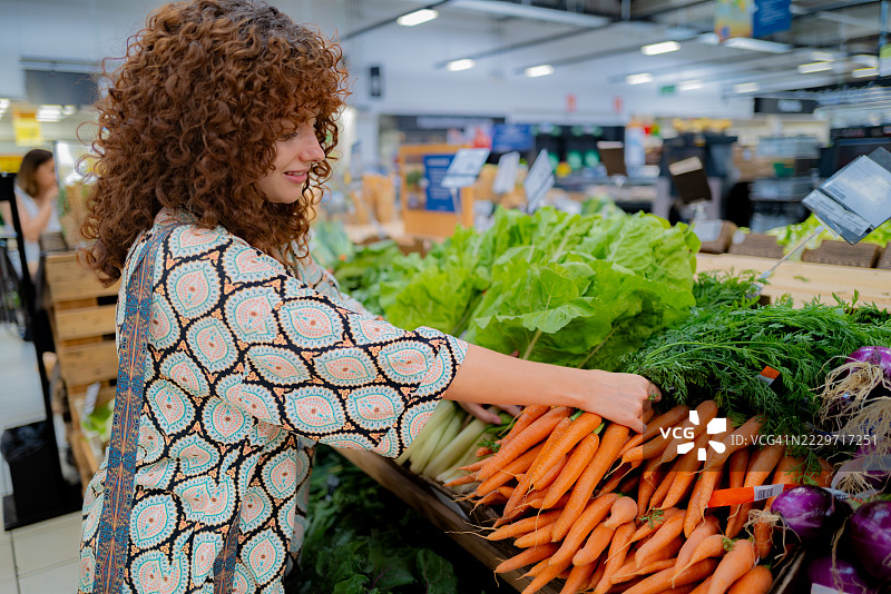 女性在超市挑选胡萝卜，购物概念图片素材
