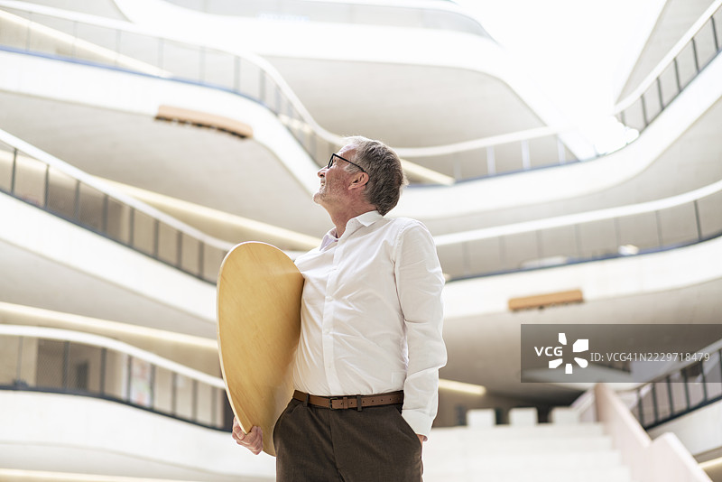 在办公室走廊里站着的商人和冲浪板图片素材