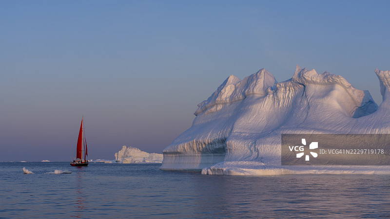 红色帆船与迪斯科湾巨大的漂浮冰山图片素材
