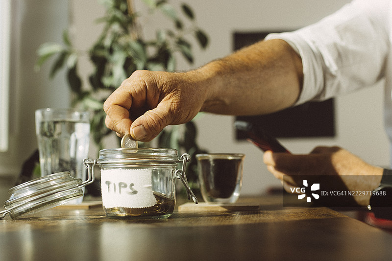 商人在咖啡店的桌子上放入小费到罐子里图片素材