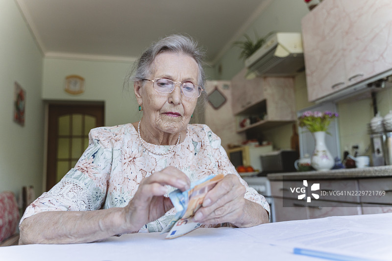 一位老年女性在房产文件上数钱图片素材