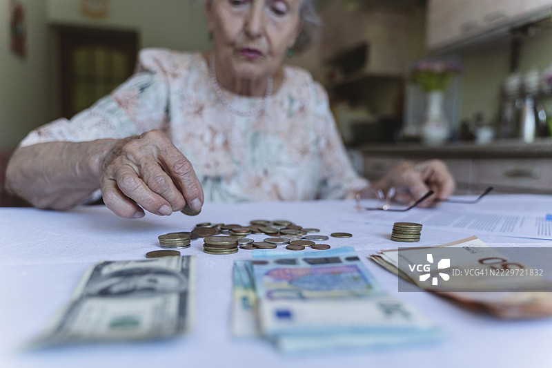 老年女性在家中桌子上数硬币图片素材