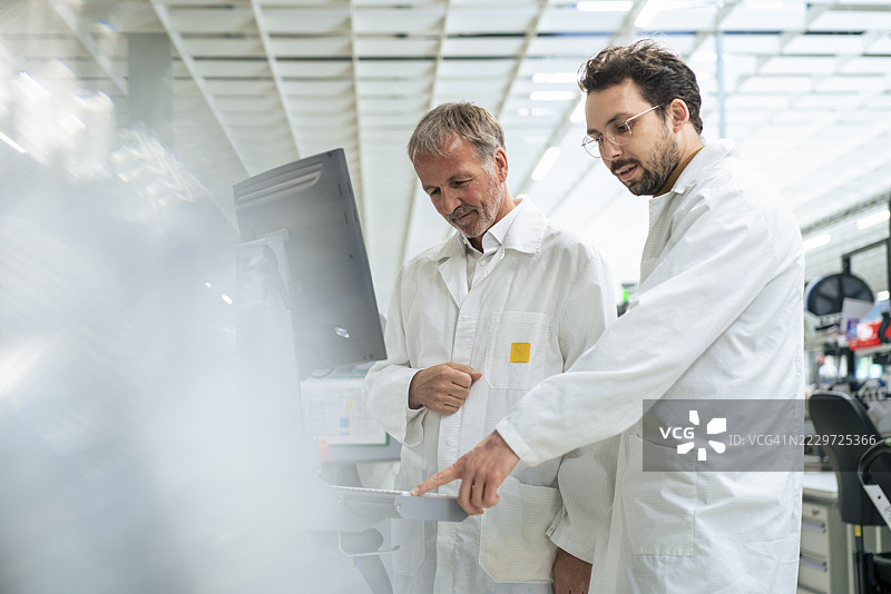 工程师与同事在工业中操作机器图片素材