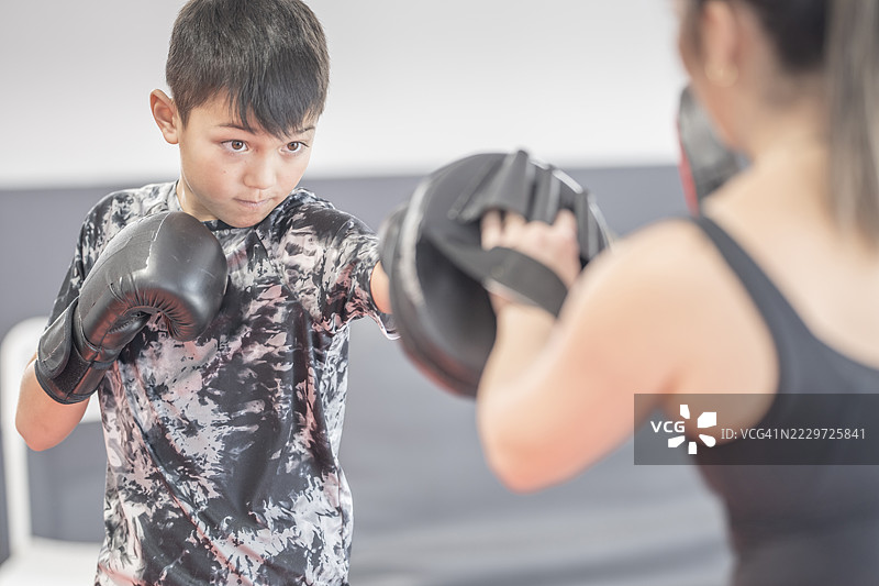 年轻男孩与教练一起练习拳击技巧，使用拳击手套图片素材