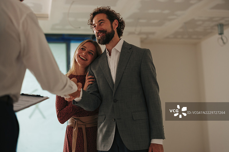 快乐的情侣与房地产经纪人握手，购买新公寓图片素材
