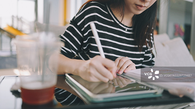 大学女孩在公共图书馆里使用笔记本电脑和智能手机与聊天机器人AI技术一起做作业图片素材