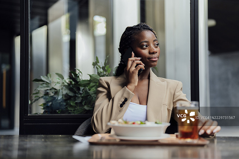 深思熟虑的女商人在咖啡厅里打手机。图片素材