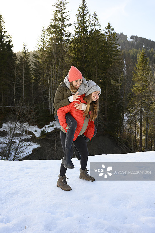 快乐的女人在雪地上背着朋友图片素材