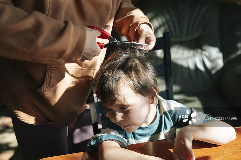 成年人在室内给一个哭泣的孩子剪头发图片素材