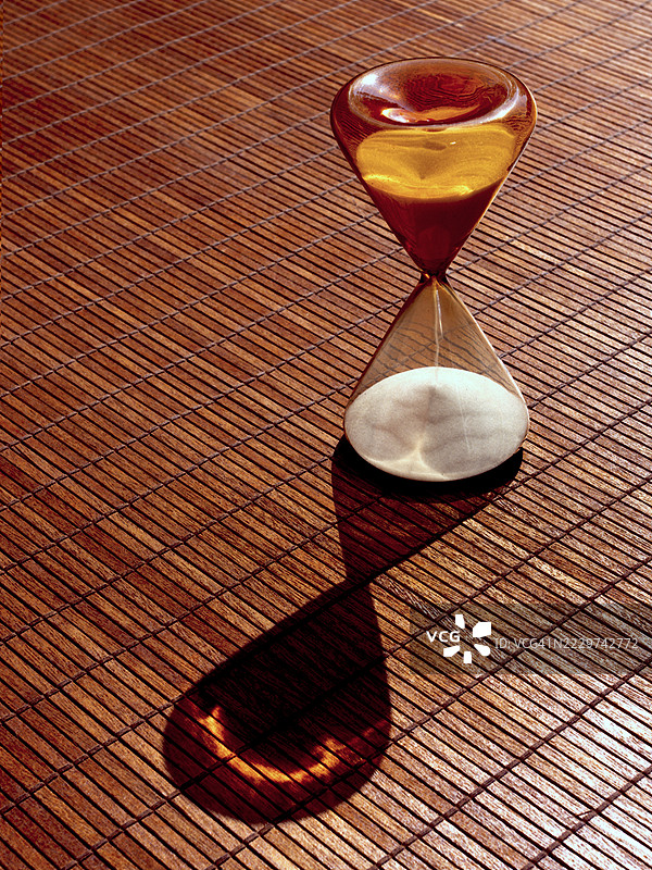 沙漏在金色时光中投射在竹席上的阴影图片素材