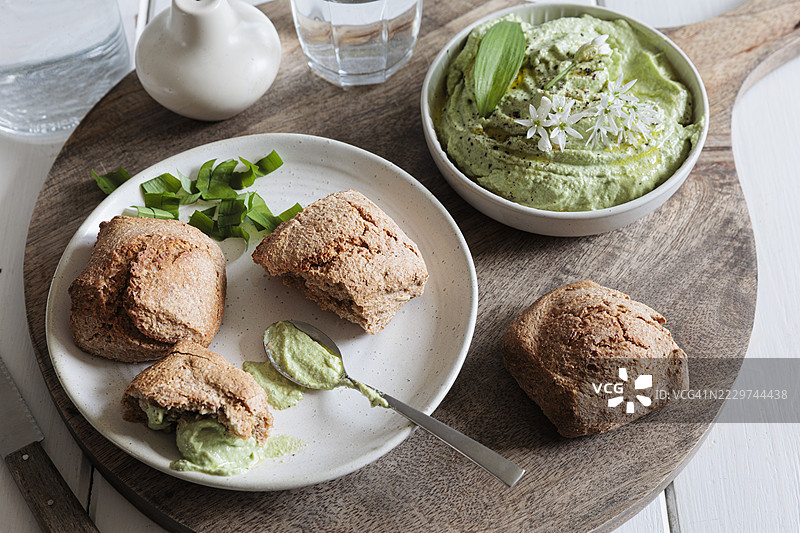 自制面包卷配野蒜蘸酱和香草奶油奶酪，摆放在木板上图片素材