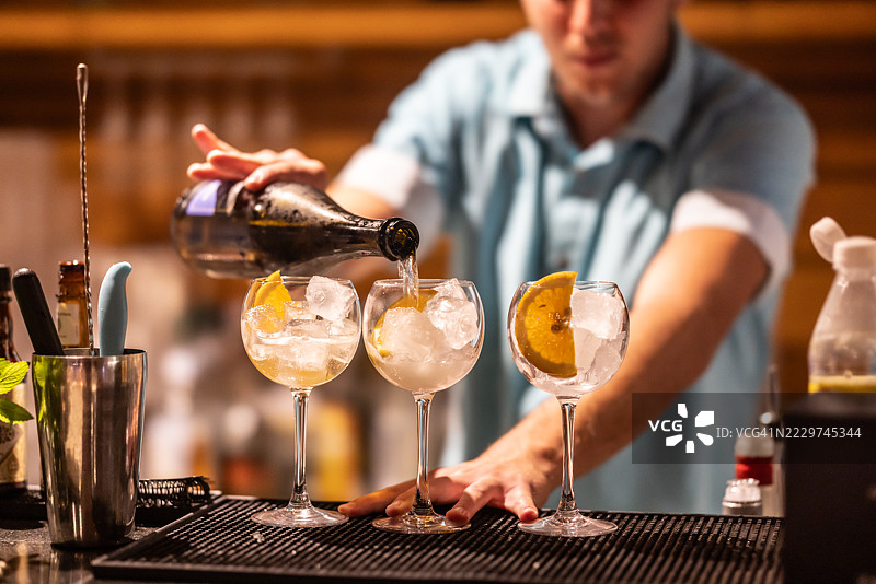 调酒师准备阿佩罗尔斯普利茨鸡尾酒，并将普罗塞克倒入杯中图片素材