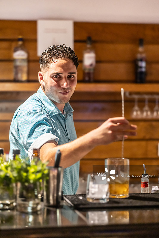 调酒师在酒吧台准备鸡尾酒，搅拌饮料后再加入苏打水。图片素材