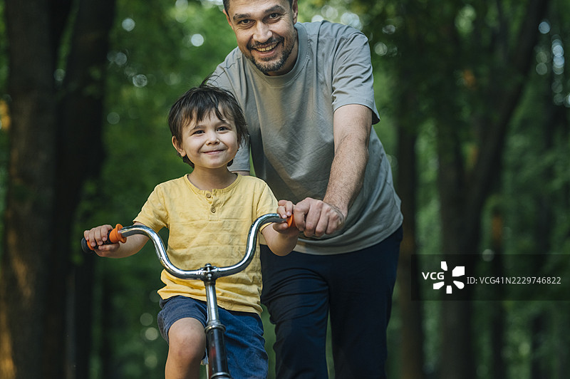 父亲在公园里教儿子骑自行车图片素材